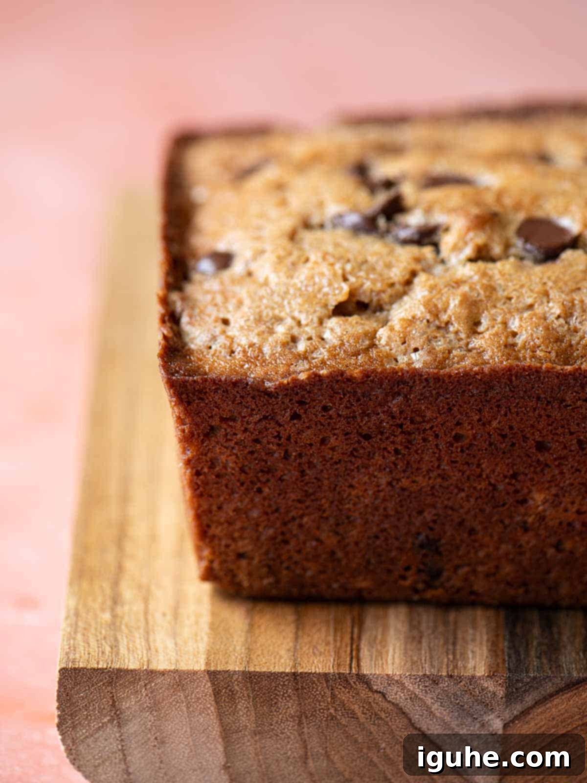 Golden Chocolate Chip Loaf 11 Side view of a chocolate chip loaf on a wood board.