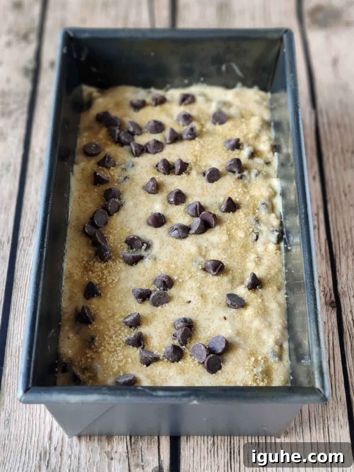 Golden Chocolate Chip Loaf 9 Prepared batter in a metal loaf pan on a wood surface.