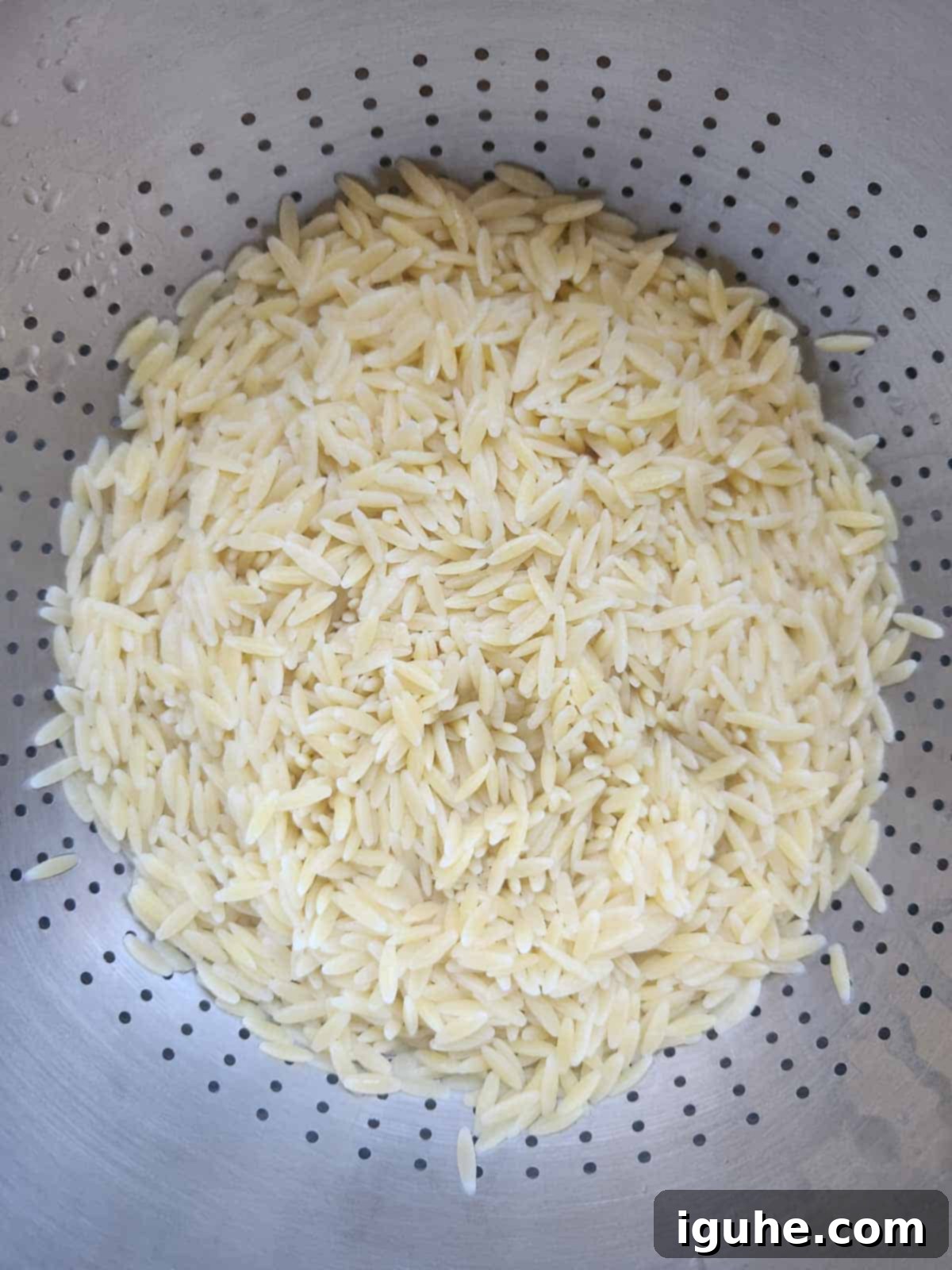 Vibrant Pesto Orzo Bowl 4 Cooked and drained orzo pasta cooling in a colander, ready to be mixed into the salad.