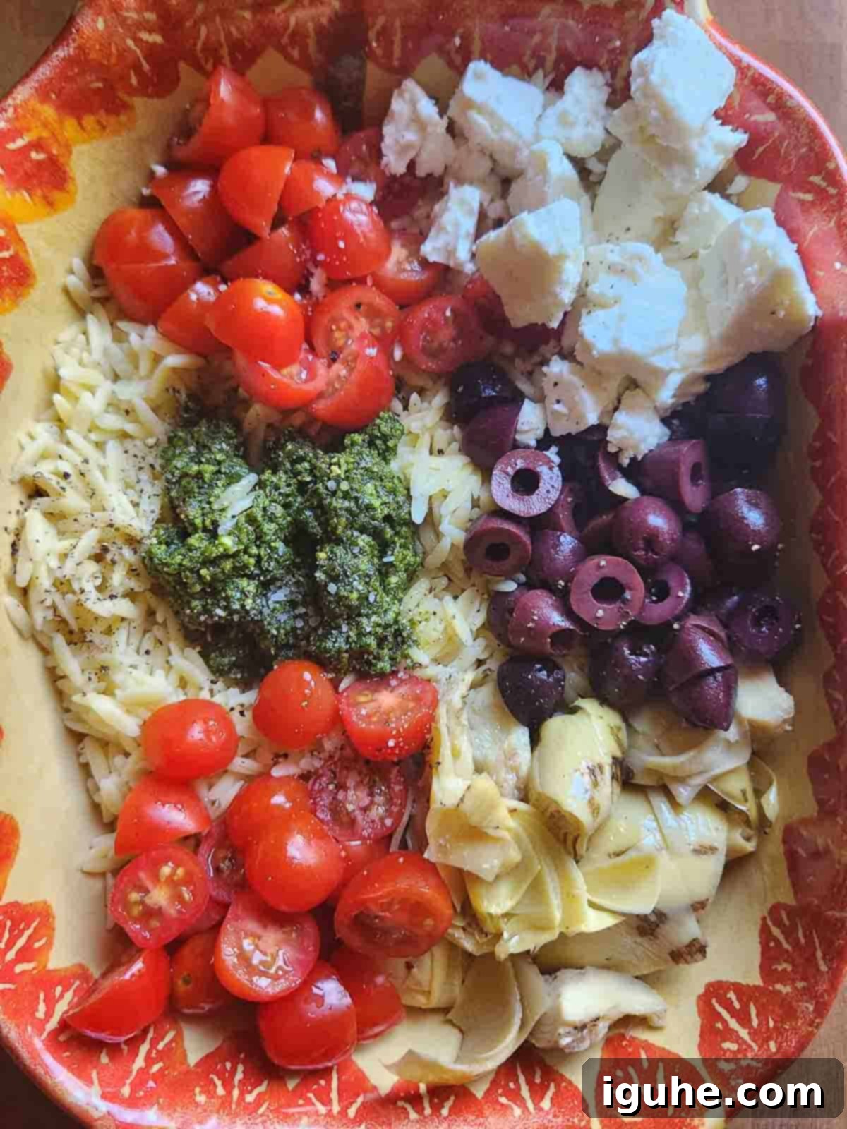 Vibrant Pesto Orzo Bowl 5 All salad ingredients, including cooked orzo, cherry tomatoes, feta, artichokes, and olives, gathered in a large mixing bowl.