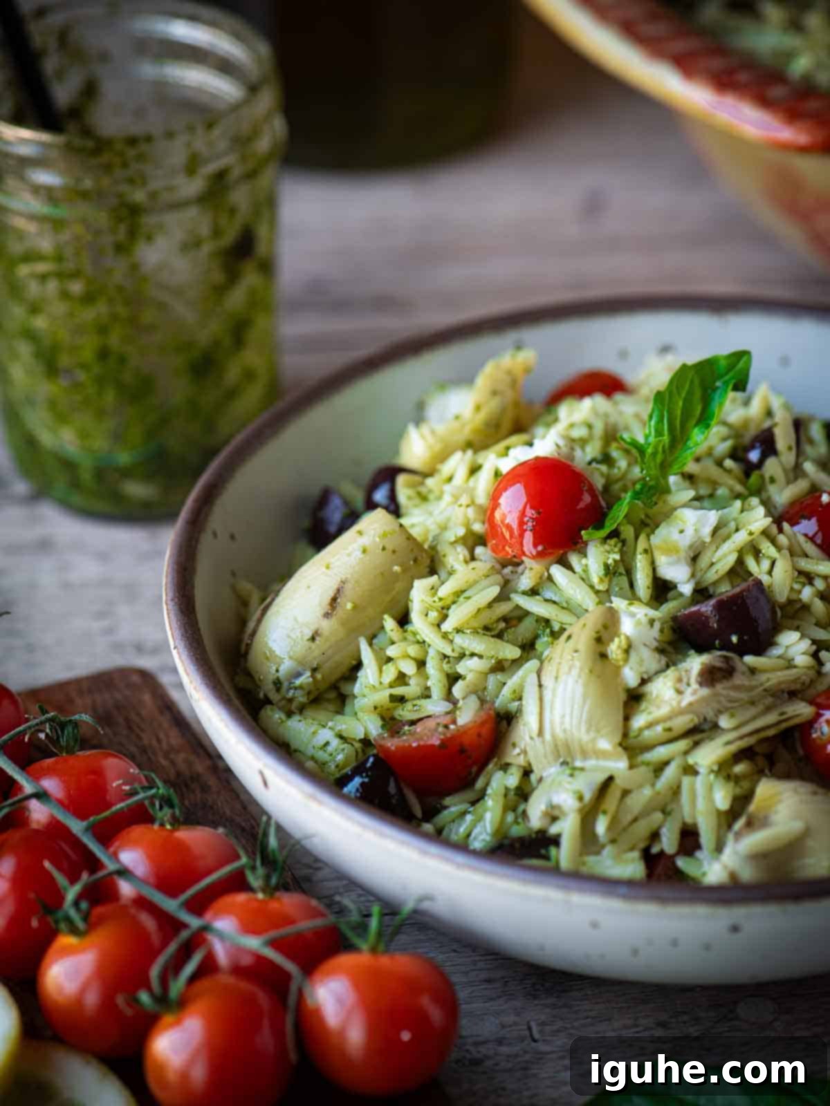 Vibrant Pesto Orzo Bowl 6 Close-up shot of Orzo Pesto Salad, highlighting the small pasta, vibrant pesto, and cherry tomatoes, with extra tomatoes artistically placed on the side.