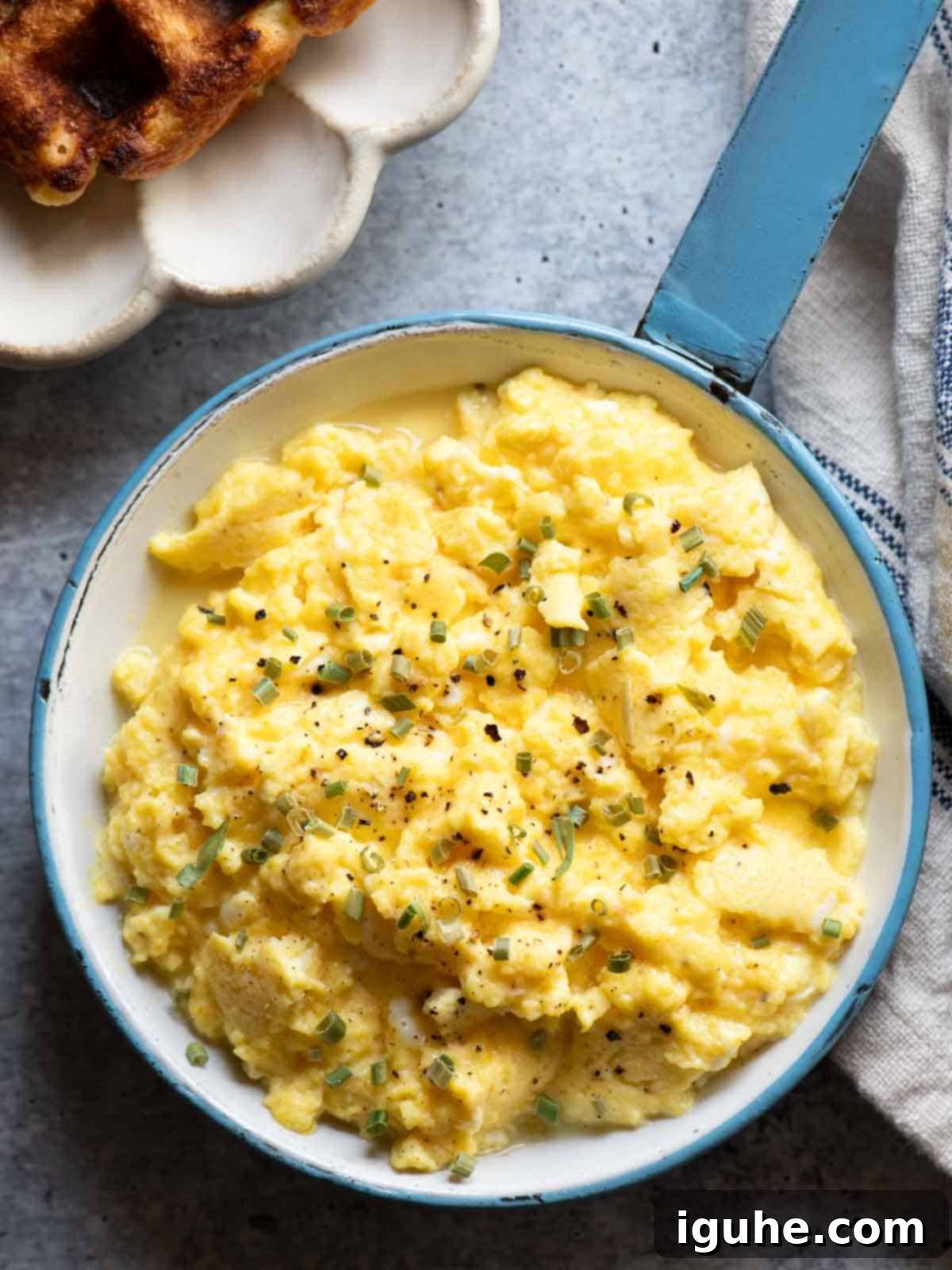 Overhead of buttermilk scrambled eggs in a blue skillet.
