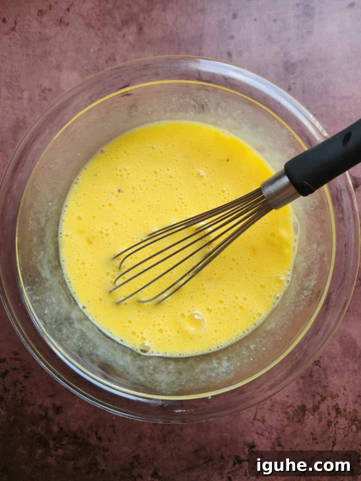 The Ultimate Buttermilk Scramble 4 Scrambled egg mixture in a clear bowl with a whisk.
