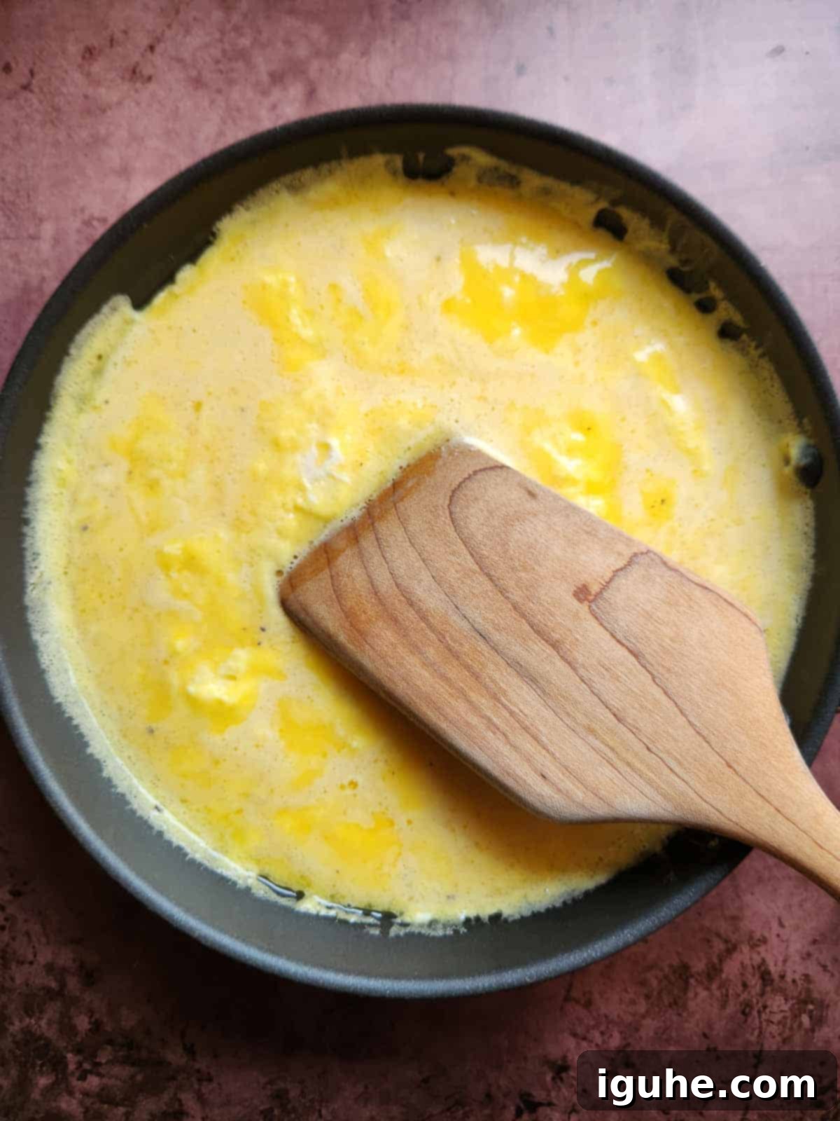 The Ultimate Buttermilk Scramble 5 Scrambled eggs in a pan with a wooden spoon.