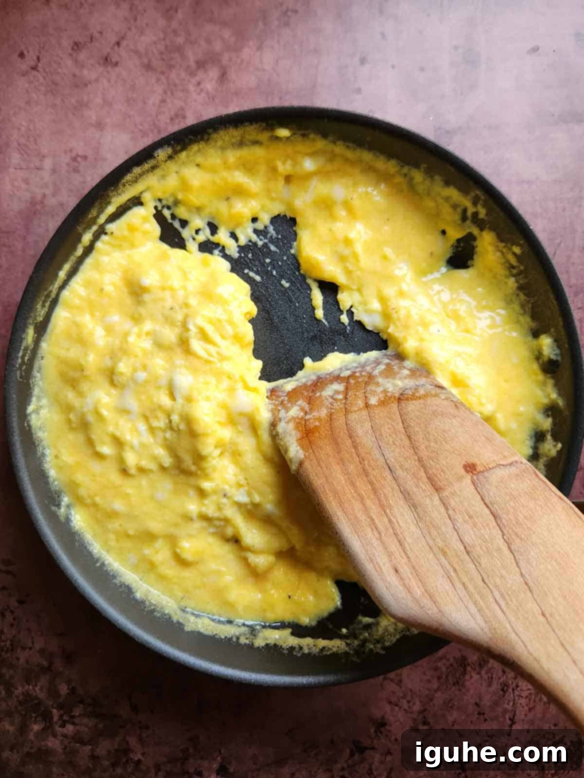 Fluffy Buttermilk Scramble 6 A wooden spoon shown moving scrambled eggs in a pan.