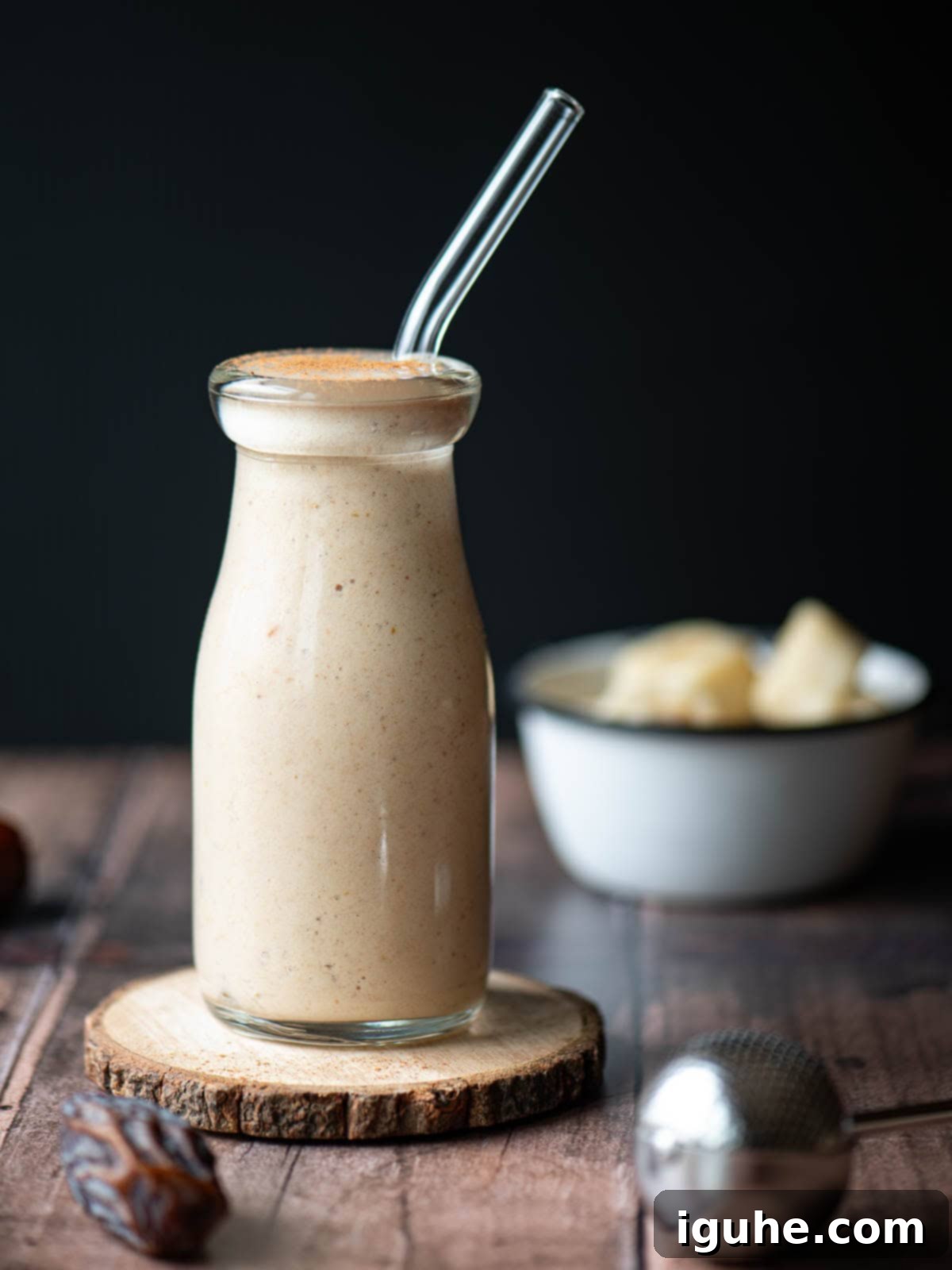Eye level smoothie in a clear glass with a glass straw on a wood surface.