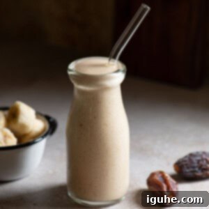 Velvet Banana Date Delight 7 Close up of a banana smoothie in a clear jug with a straw.