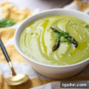 Velvety Asparagus Leek Soup 7 Close up of asparagus leek soup in a white bowl over a yellow striped linen.