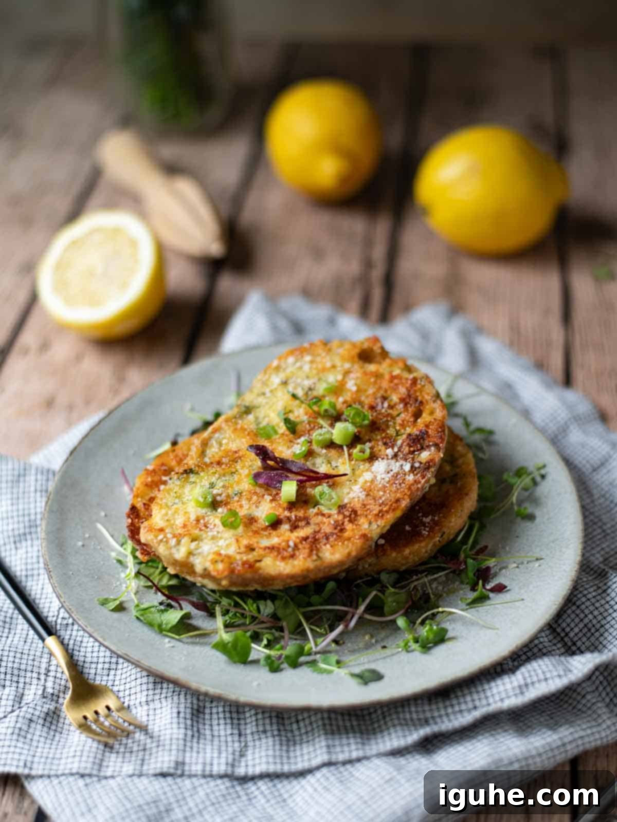 Parmesan, Lemon and Herb Savory French Toast 10 A plate of French toast over microgreens on a wooden table with lemons.