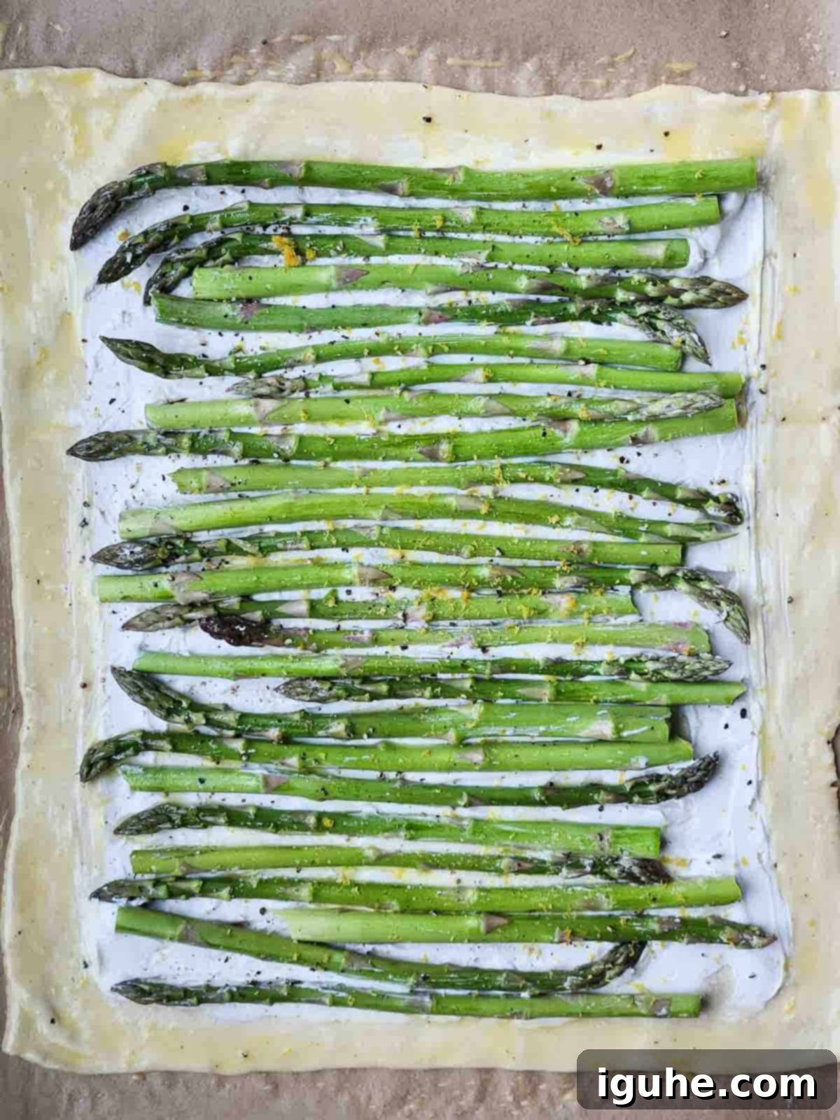 Flaky Asparagus Tart with Tangy Goat Cheese 3 Uncooked puff pastry with goat cheese and asparagus on top.