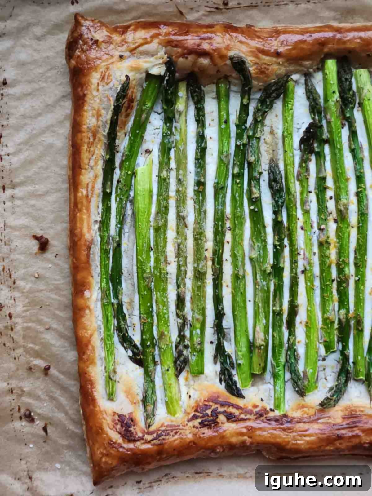 Flaky Asparagus Tart with Tangy Goat Cheese 5 Asparagus and goat cheese puff pastry on parchment paper.