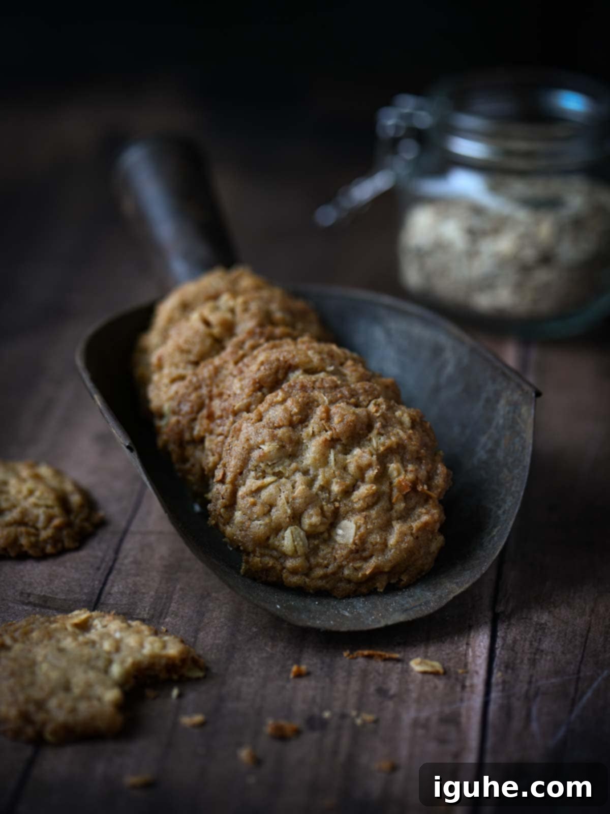 Golden brown coconut oatmeal cookies stacked in a metal scoop on a rustic wooden surface, highlighting their delicious texture.