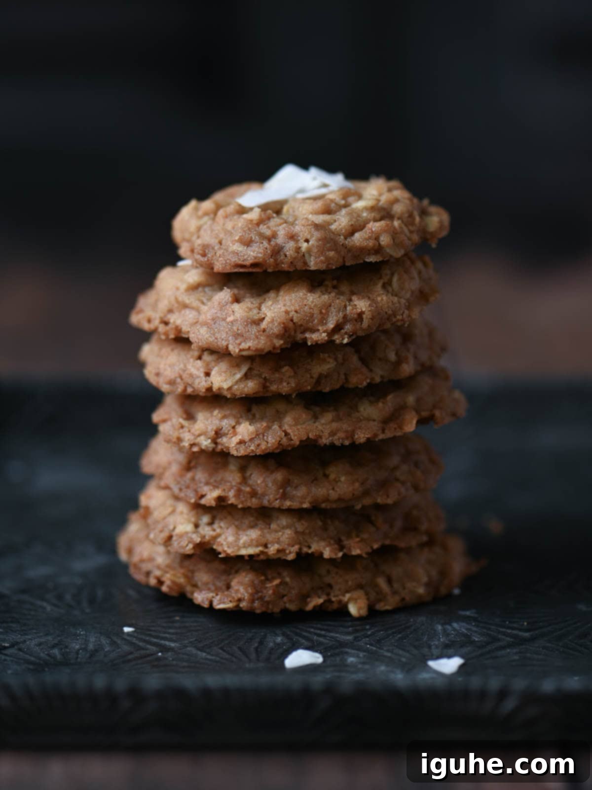 A stack of golden coconut oatmeal cookies on a metal tray, garnished with fresh coconut flakes and a hint of vanilla.