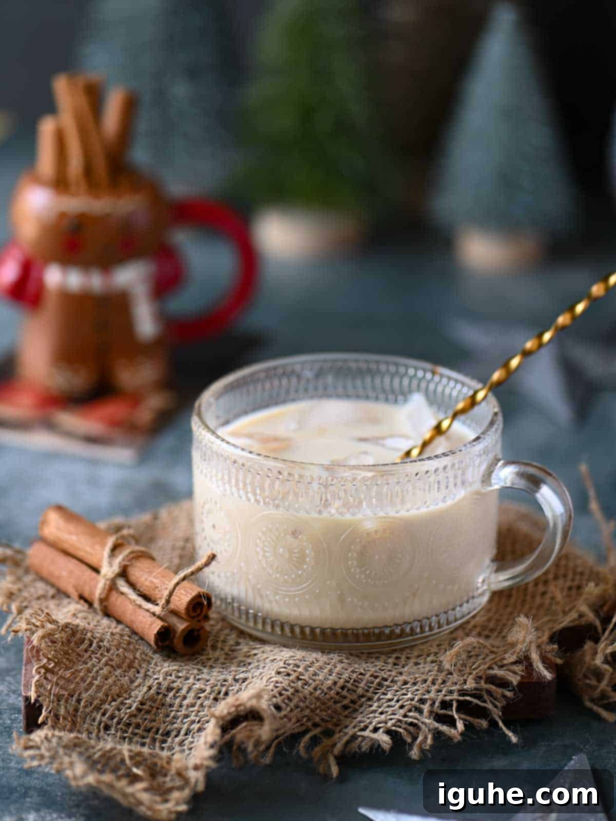 An eggnog white Russian in a clear class with a stirrer in it.