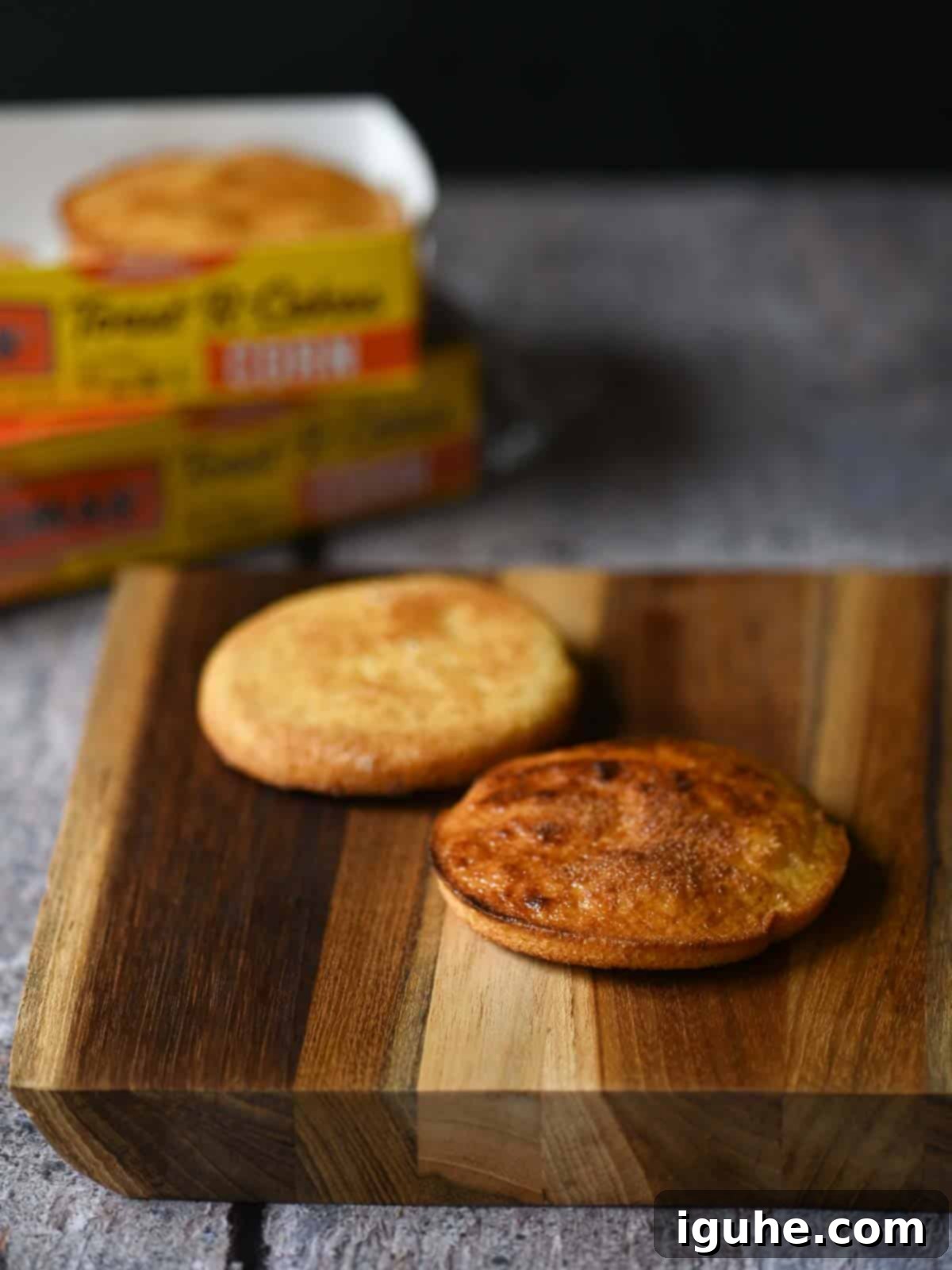 Two golden-brown toasted corn cakes, fresh out of the toaster, resting on a rustic wooden board, ready for butter and toppings.