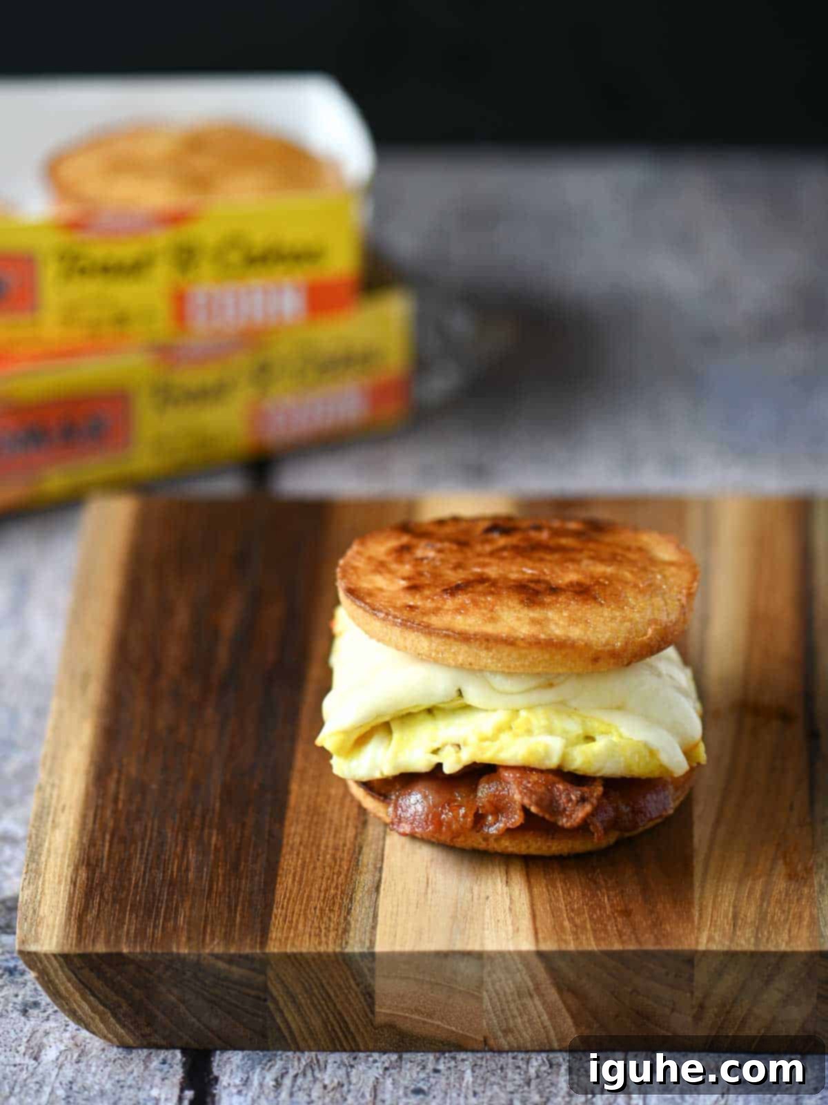 A fully assembled Corn Toaster Cake Breakfast Sandwich, topped with a drizzle of maple syrup, resting on a wooden cutting board, ready to be enjoyed.