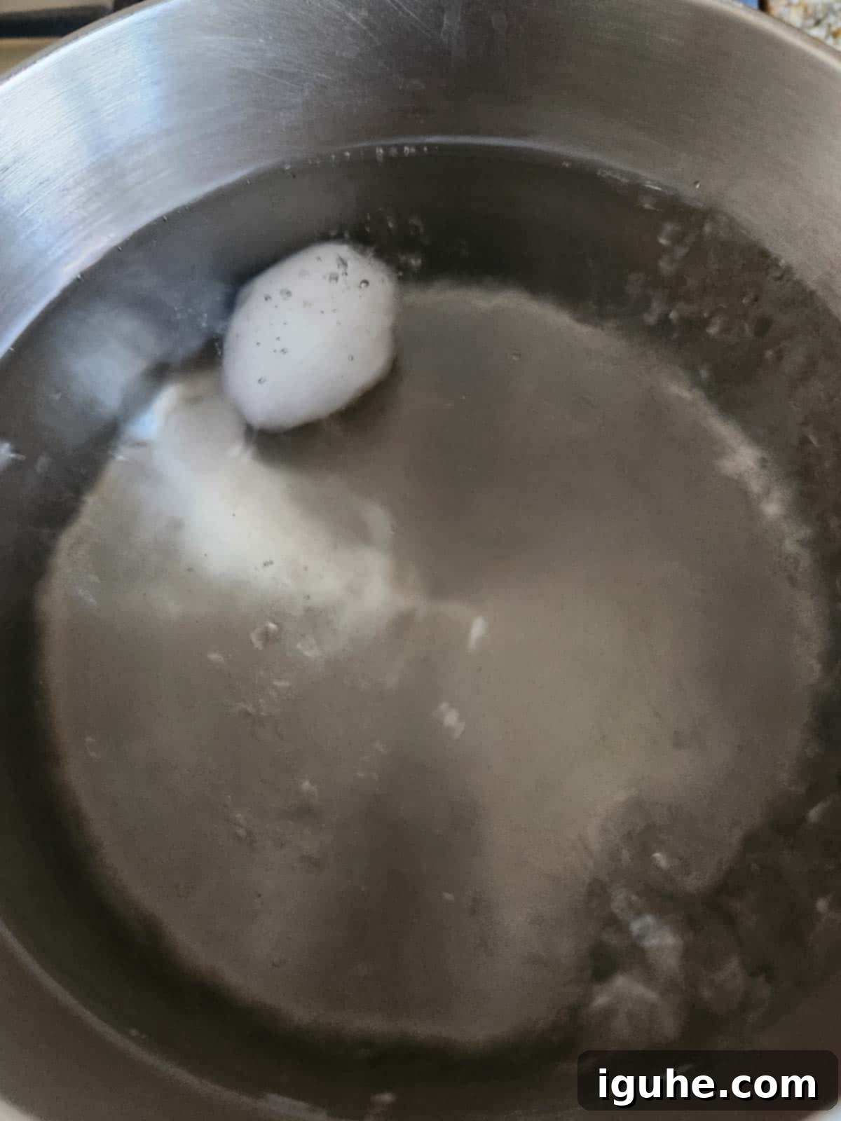 Perfectly Runny Eggs With Toasted Rye 4 A single egg submerged in a pot of gently boiling water.