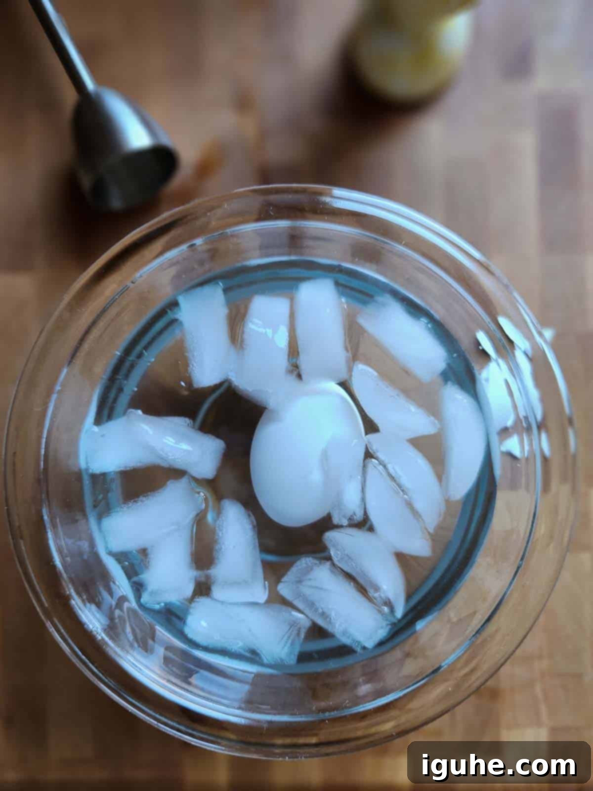 Perfectly Runny Eggs With Toasted Rye 5 Overhead shot of a soft boiled egg resting in a clear bowl filled with ice water.