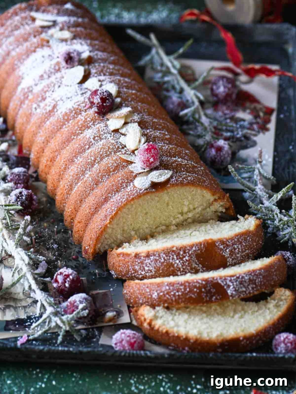 Angled view of almond cake with sugared cranberries and rosemary on the side. Perfectly showcasing the deliciousness of this Scandinavian almond cake recipe.