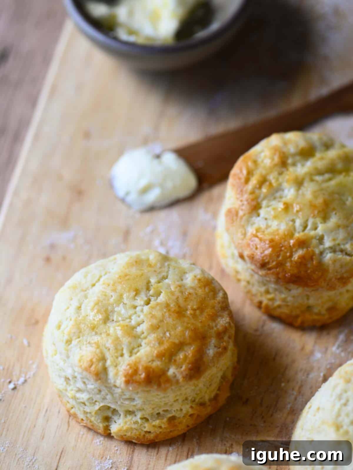 Cake Flour Biscuits 3 An angled view of fluffy cake flour biscuits arranged on a cutting board with a pat of butter.