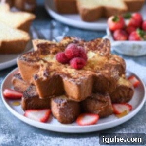 A stack of French toast with berries on a white plate on a blue surface.