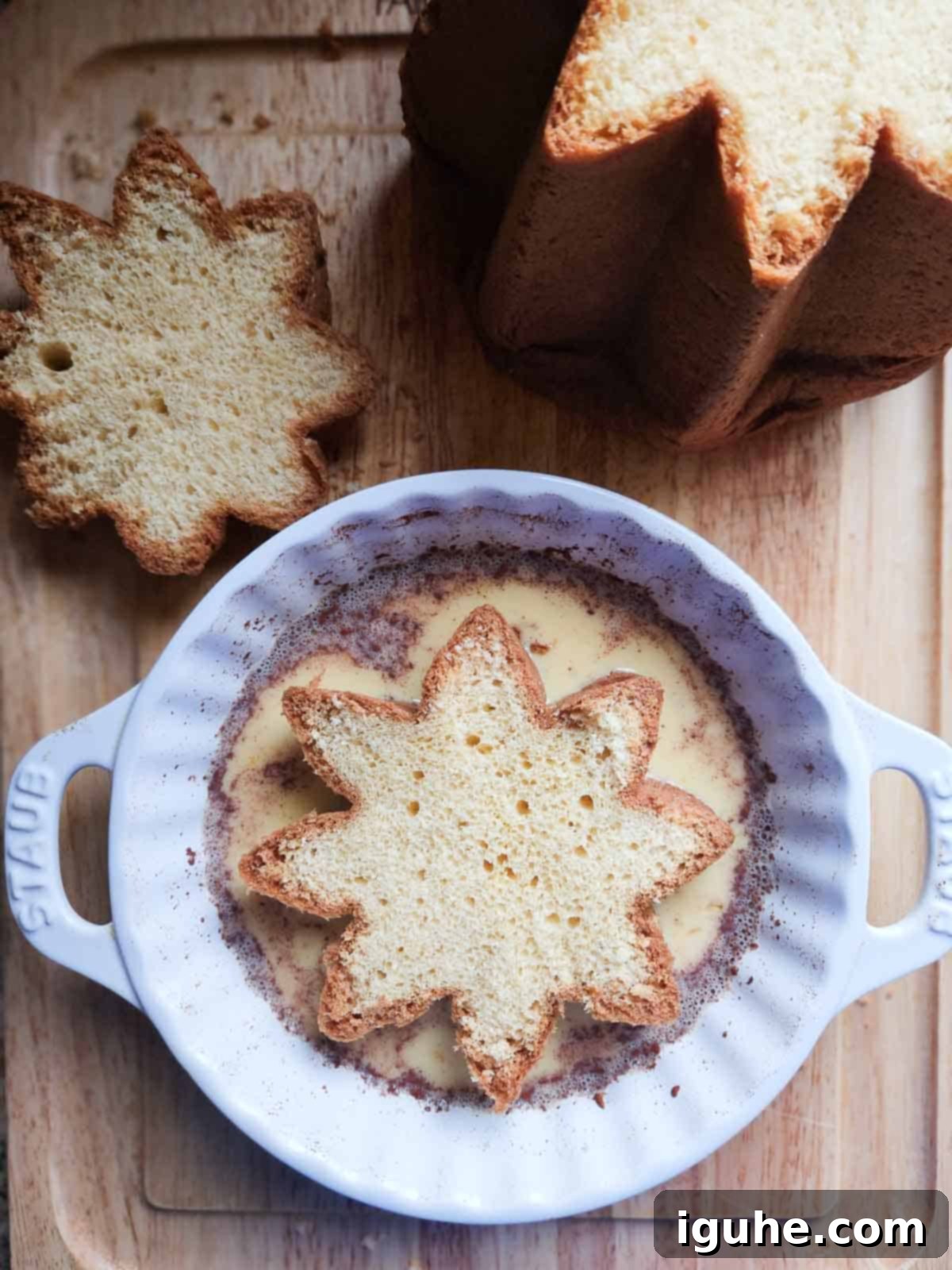 A slice of pandoro in french toast custard in a white dish.
