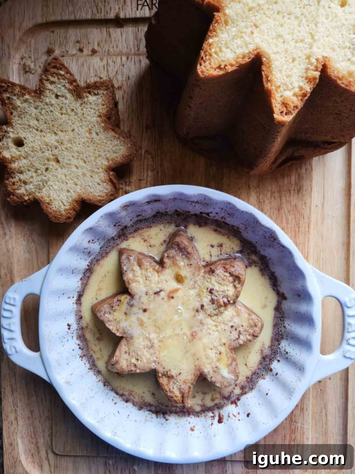 A slice of pandoro in french toast custard in a white dish.