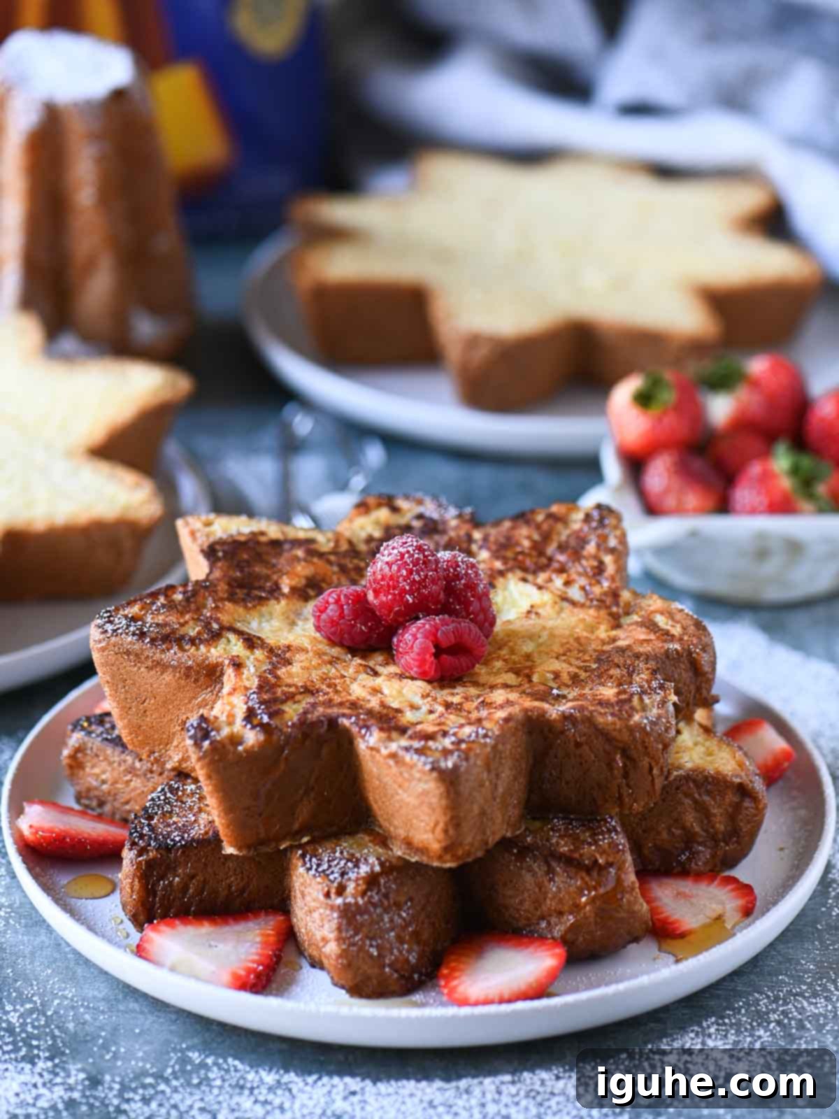 Pandoro French toast stacked on a plate with lots of red berries.