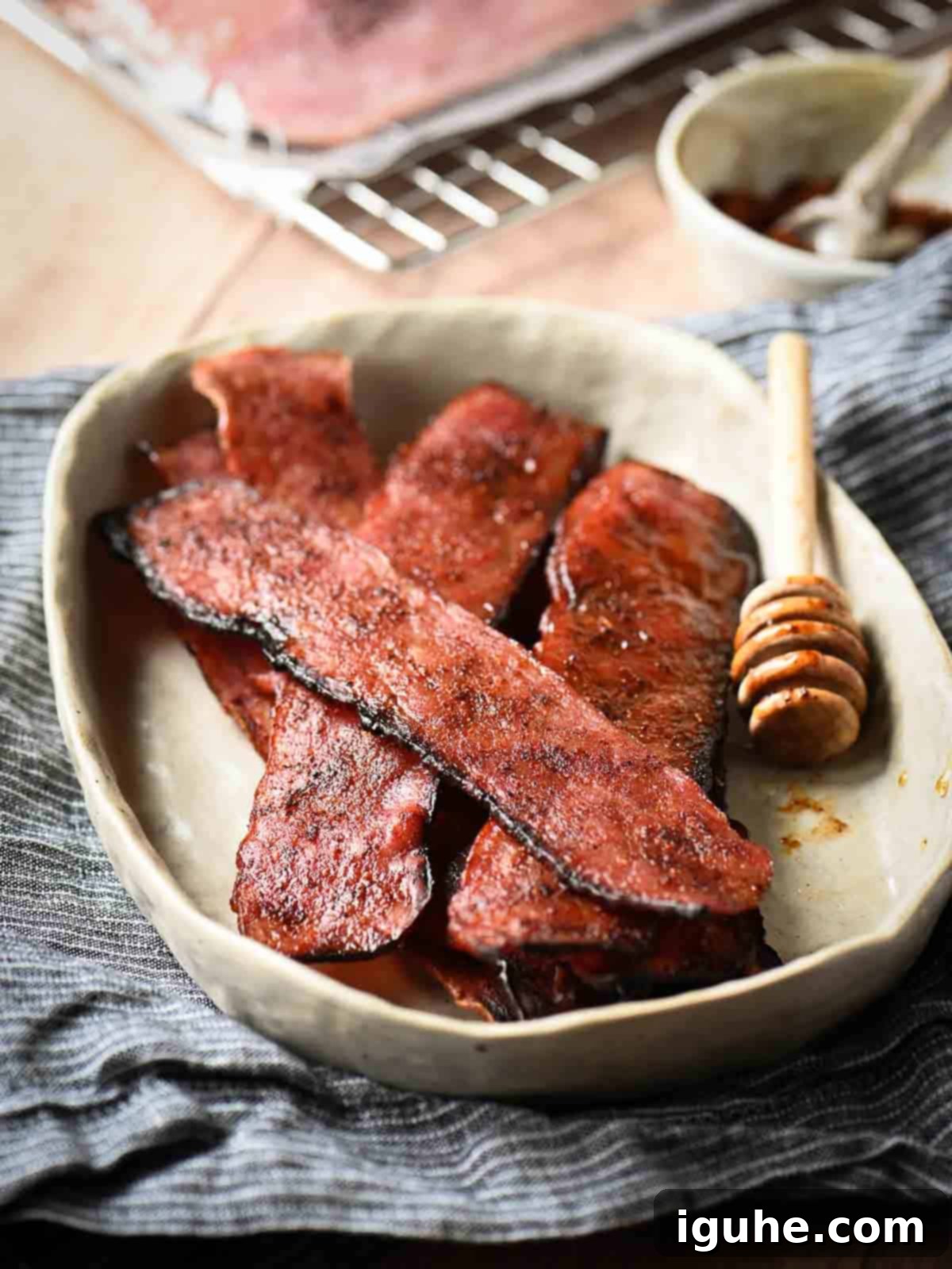 Honey Chipotle Turkey Bacon Bliss 2 Strips of honey chipotle turkey bacon in a beige bowl on top of a blue napkin, showcasing the sweet and smoky flavors.