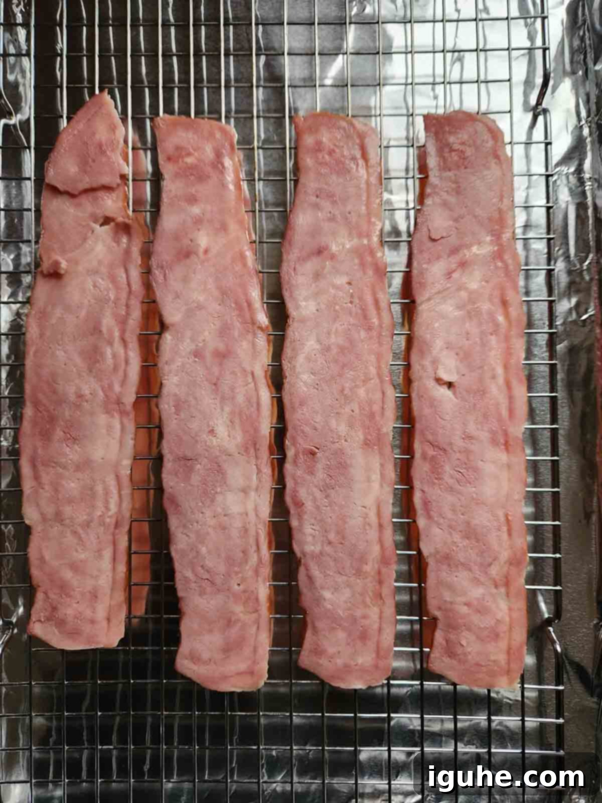 Honey Chipotle Turkey Bacon Bliss 4 Turkey bacon arranged in a single layer on a wire rack placed on top of a baking sheet, ready for seasoning.