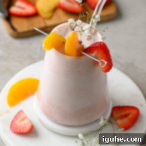 Strawberry Peach Bliss Smoothie 9 Angled view of a strawberry peach smoothie in a clear glass, ready to enjoy.