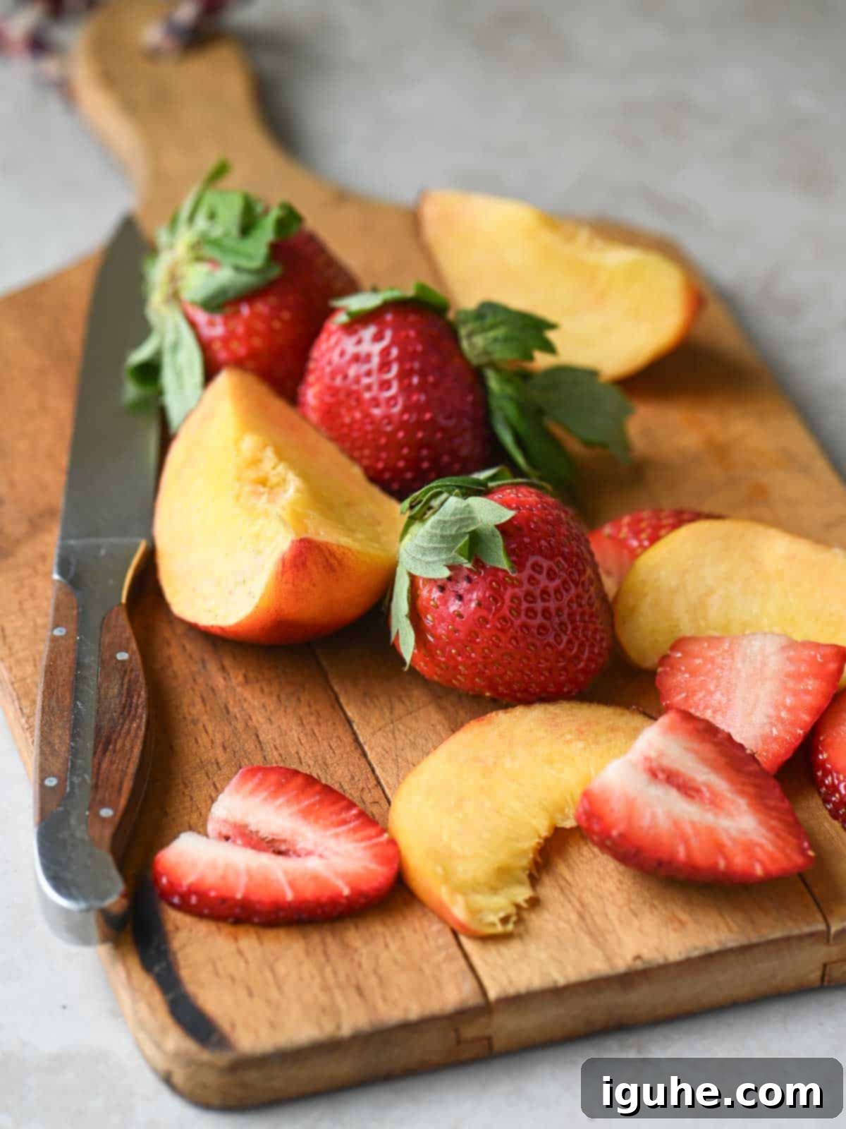 Strawberry Peach Bliss Smoothie 3 A close-up shot of freshly sliced peaches and strawberries on a wooden cutting board.