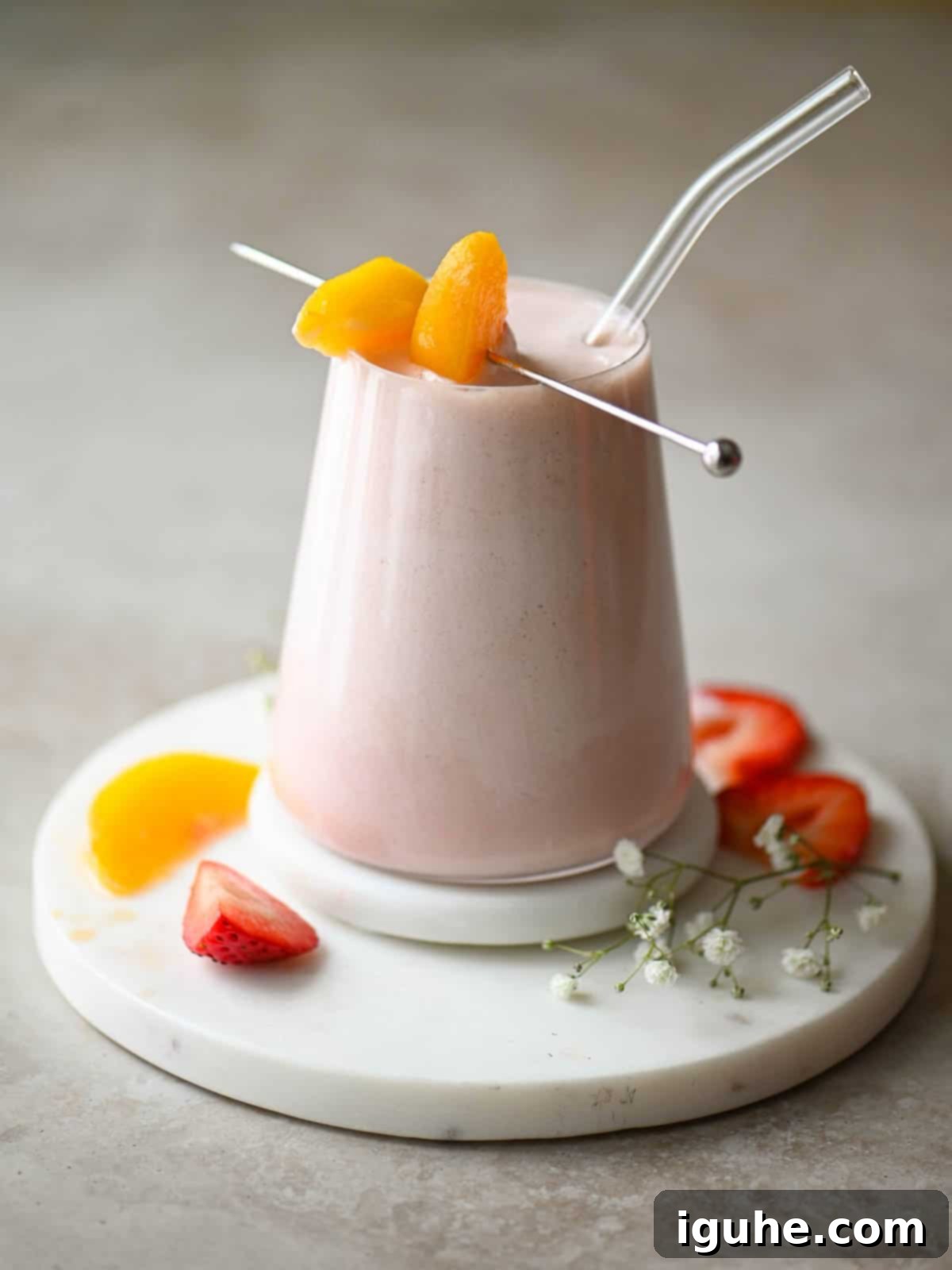 Strawberry Peach Bliss Smoothie 7 A close-up, eye-level view of a refreshing smoothie in a clear glass with a clear straw.