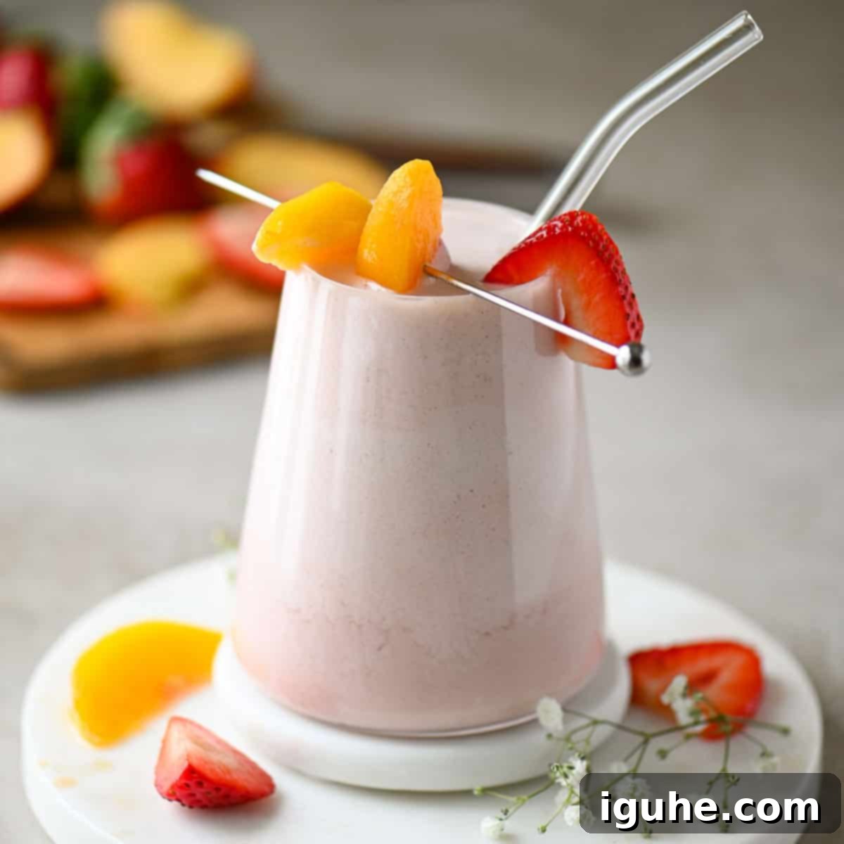 Strawberry Peach Bliss Smoothie 8 A close-up of a strawberry peach smoothie in a clear glass, placed on a marble slab.