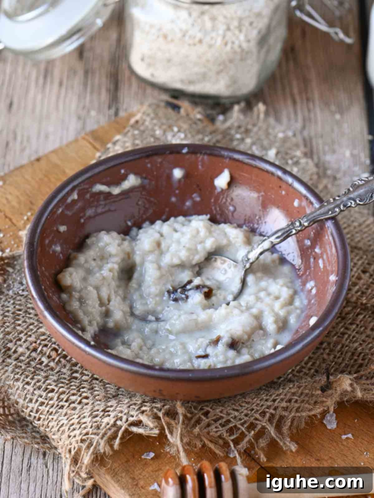 Dates and Honey: A Twist on Classic Scottish Oatmeal 8 A half-eaten bowl of Scottish oatmeal in a rustic brown bowl, with a spoon resting to the side.