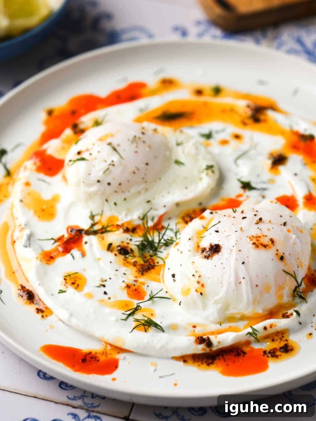 Chili Butter Poached Eggs with Garlicky Yogurt 2 Close-up of chili-poached eggs on a white dish, showcasing the vibrant colors and textures.