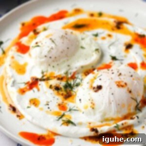 Chili Butter Poached Eggs with Garlicky Yogurt 8 Two chili butter poached eggs on a white dish, garnished with fresh dill.