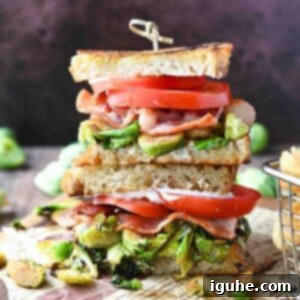 Crispy Brussels Sprout BLT 9 Stacked brussel sprout BLT sandwiches on a wooden board.