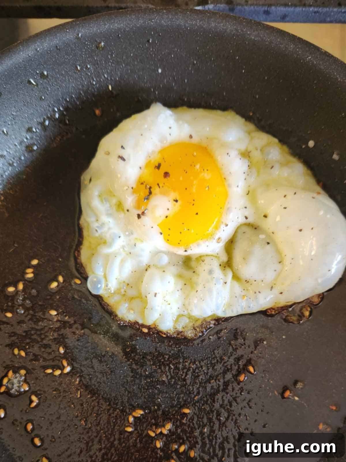 A perfectly fried egg sizzling in a black skillet, showcasing the crispy edges and golden yolk infused with the aroma of za'atar spice.